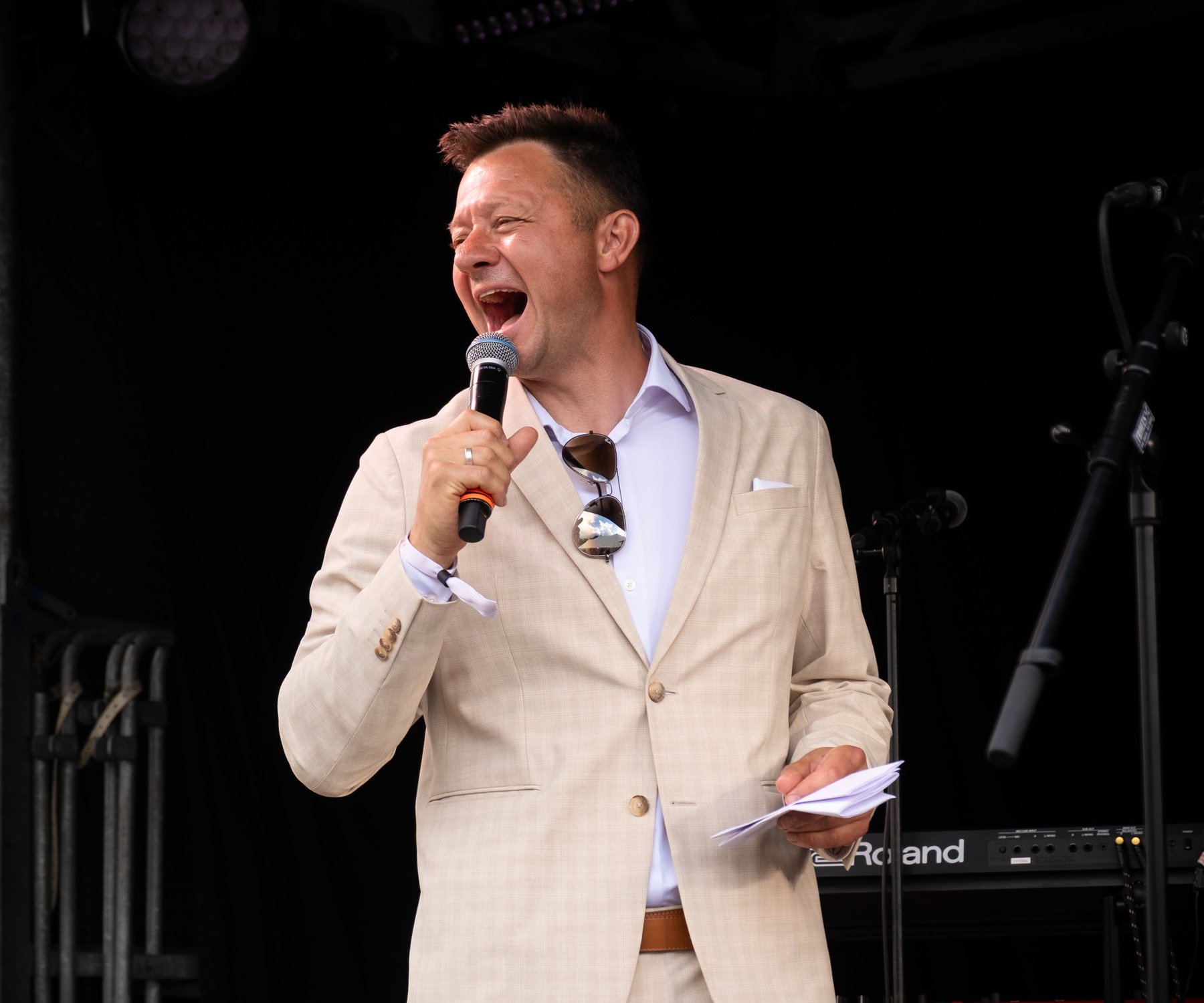 Konferencier og foredragsholder Lars Godbersen på scenen i lys habit med mikrofon